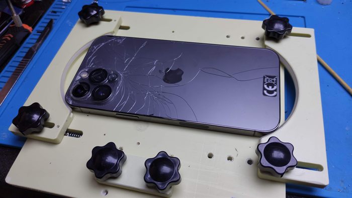 iPhone au dos cassé, maintenu sur un support de réparation